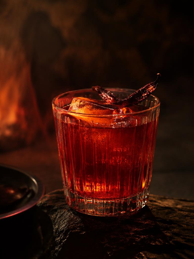 Amber red cocktail with a dried chilli garnish