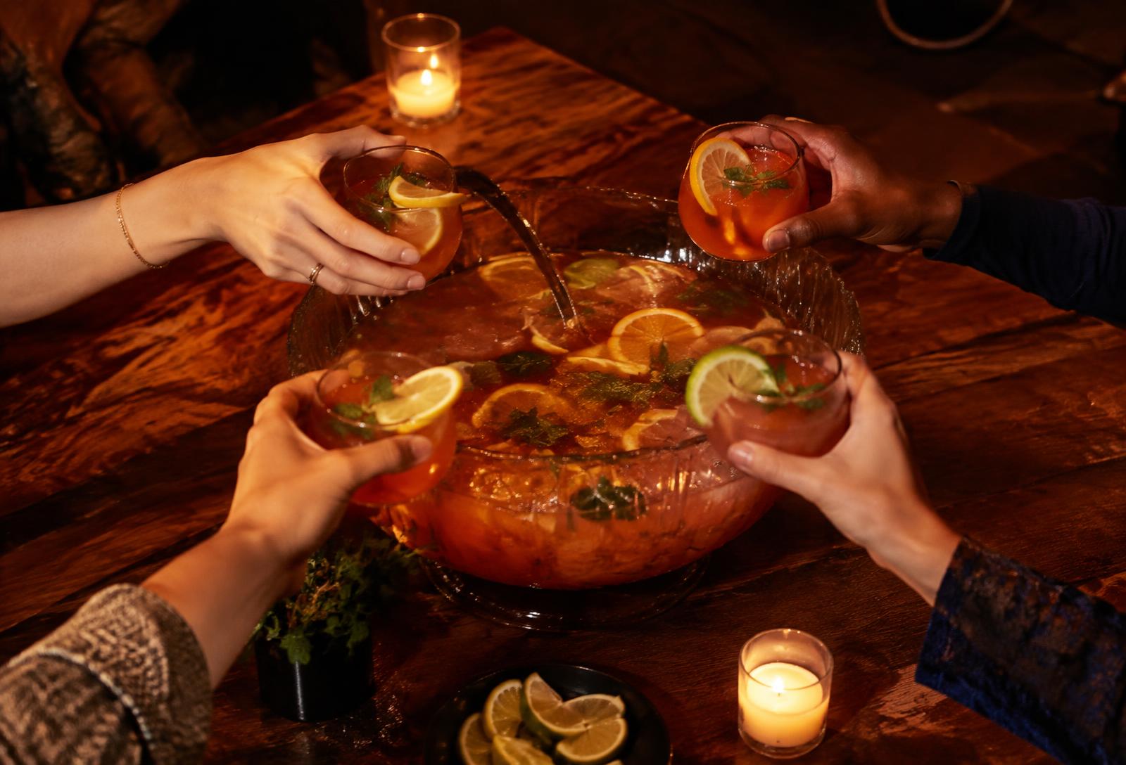 Friends sharing a punch bowl cocktail by candlelight